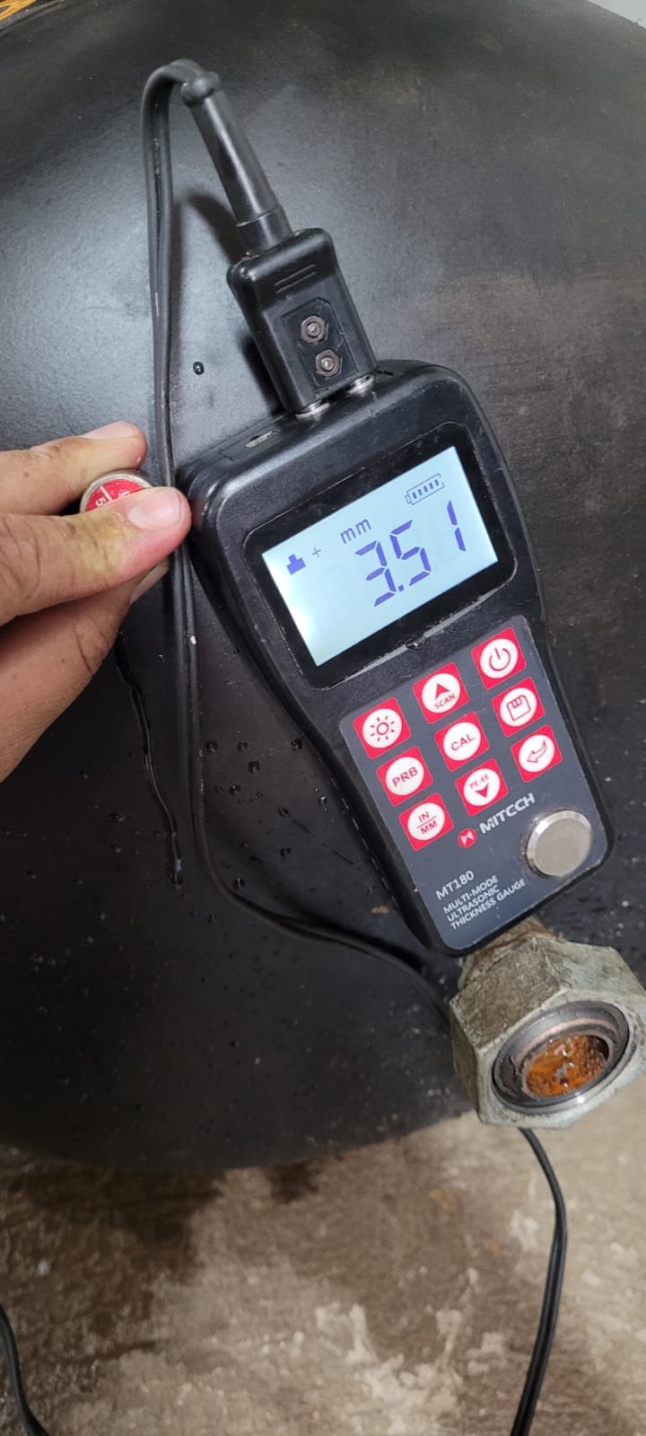 Medidor ultrassônico de espessura em operação sobre tanque de compressor preto